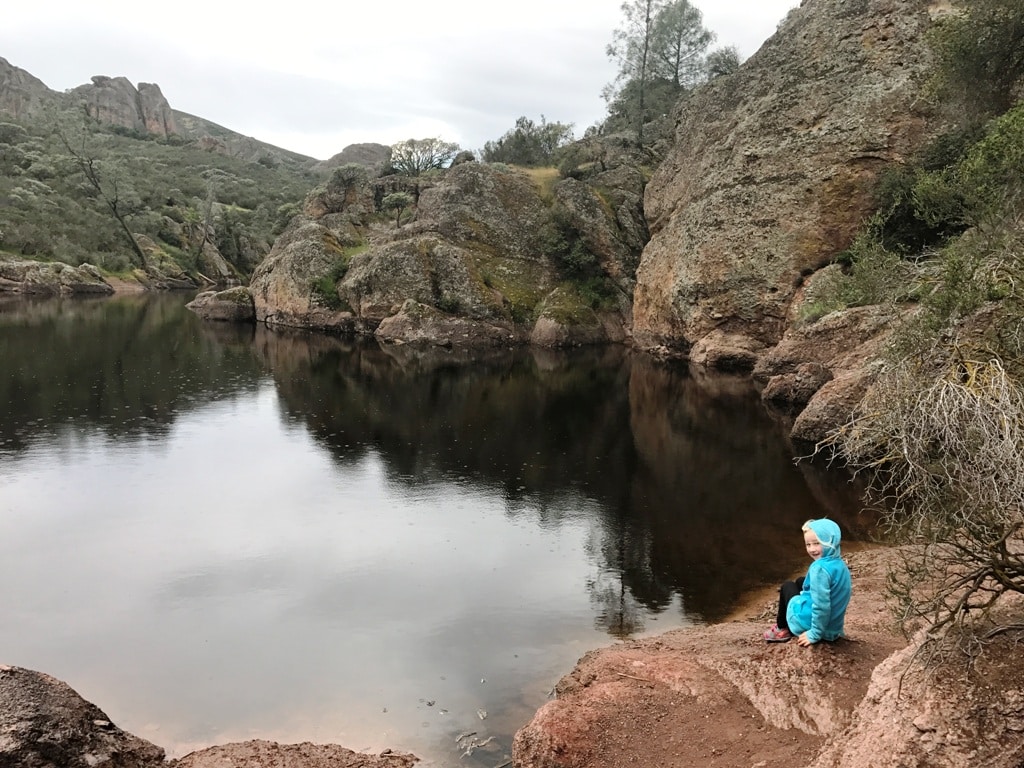 Girl Sitting By Lake In Pinnacles Best National Parks To Visit In Winter