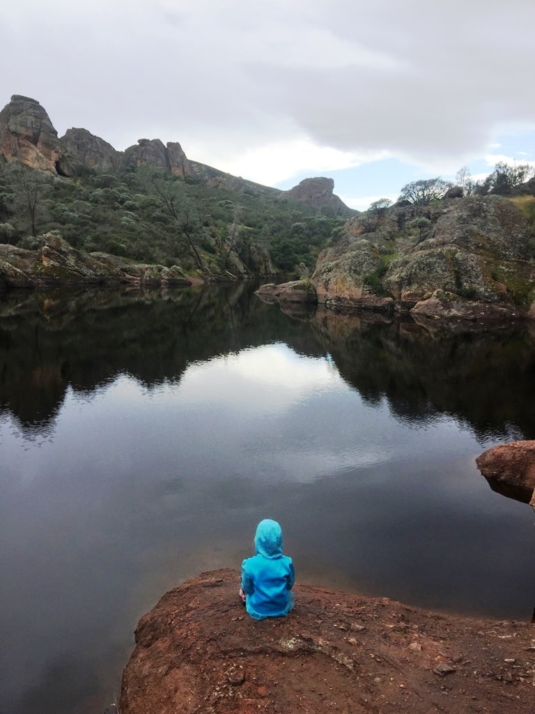 Girl Sitting On Rock In Front Of Lake In Pinnacles Warmest National Parks To Visit In Winter