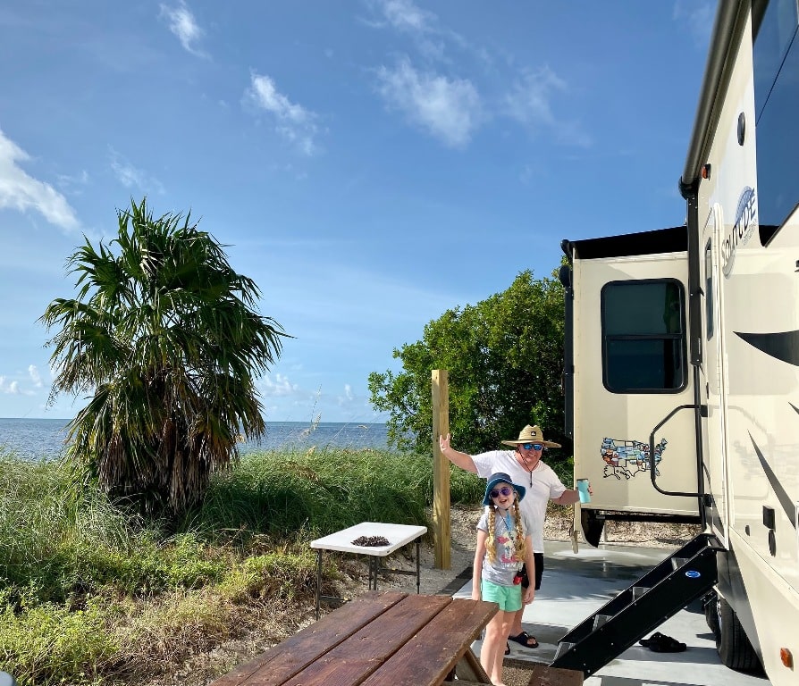 Man and girl RV camping on the ocean at state park - Arvie camping cancellations