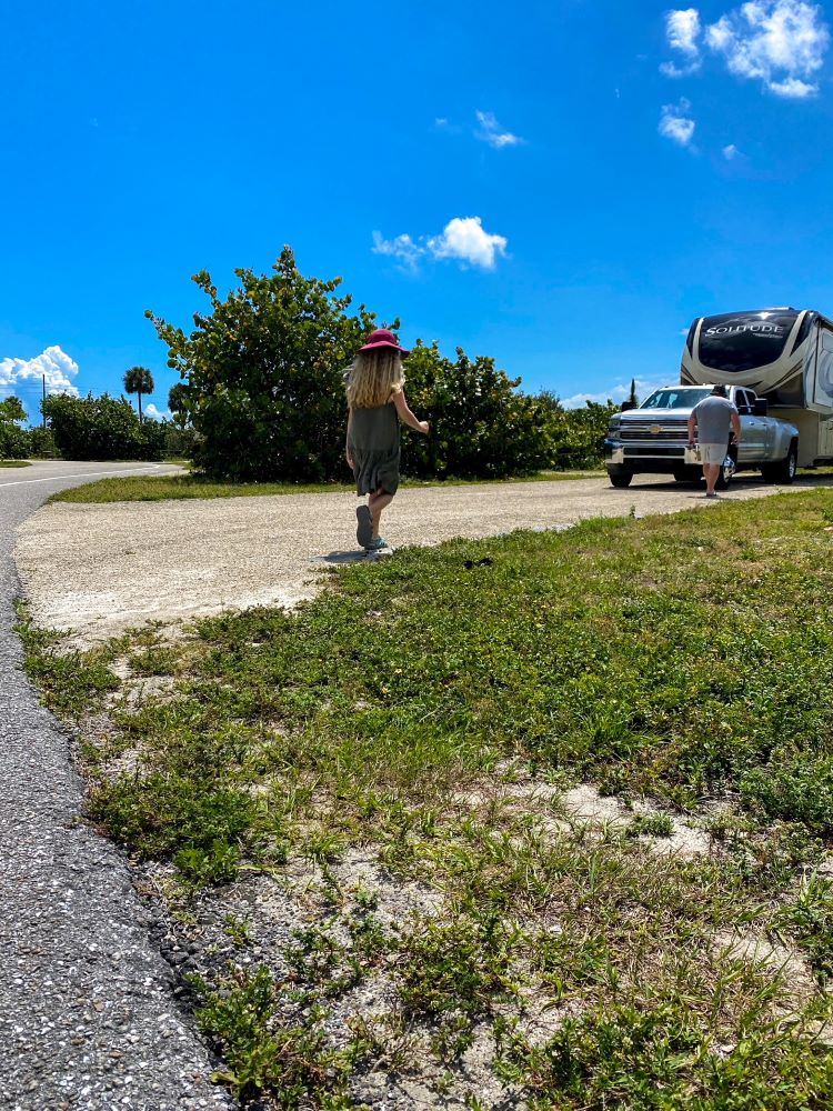 Man and girl walking in state park campsite with RV - Cost of RVing full time