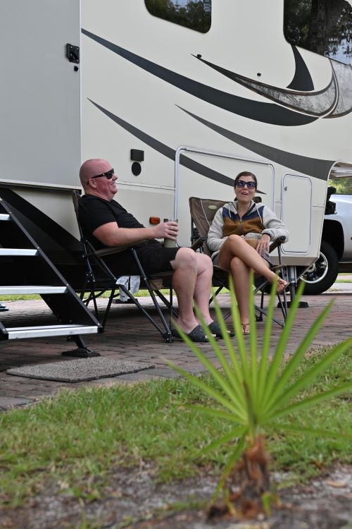 Couple having coffee in front of RV - Dangers Of Living In An RV