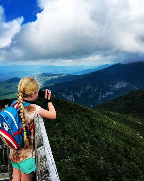 Girl photographing mountains in New Hampshire on RV trip - full-time RV dangers