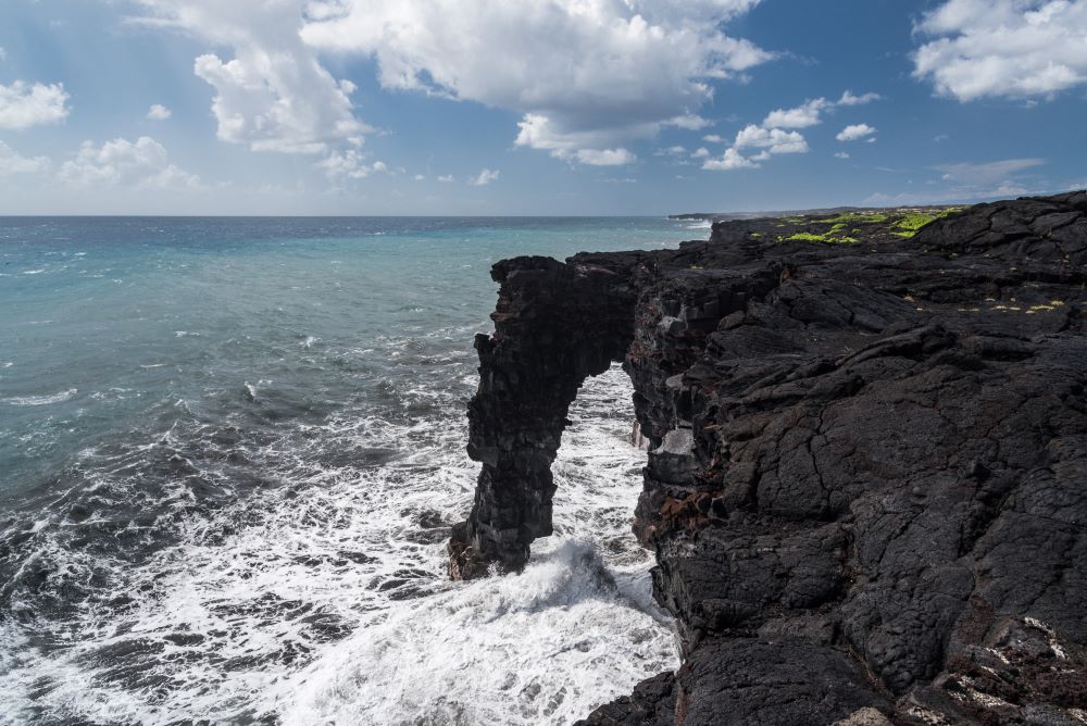 Hawaii Volcanoes National Park rocky shore with rock arch - Warm winter national parks